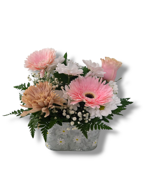 Arrangement de fleurs pastel avec gerberas roses, marguerites blanches et verdure dans un pot décoré de marguerites