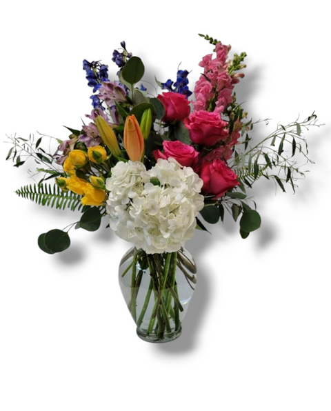 Bouquet coloré en vase avec roses fuchsia, hortensias blancs, lisianthus jaunes, lys orangés et delphiniums – modèle Vive la Vie.