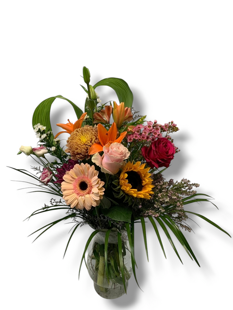 Arrangement de marguerites blanches et mini roses roses dans un vase carré rose à pois blancs.