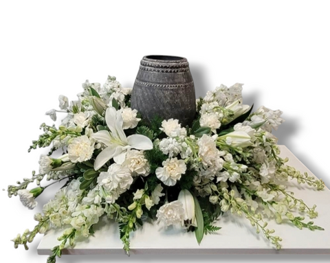 Arrangement floral blanc autour d’une urne avec lys, mufliers, œillets et verdure – modèle Cercle de Lumière.