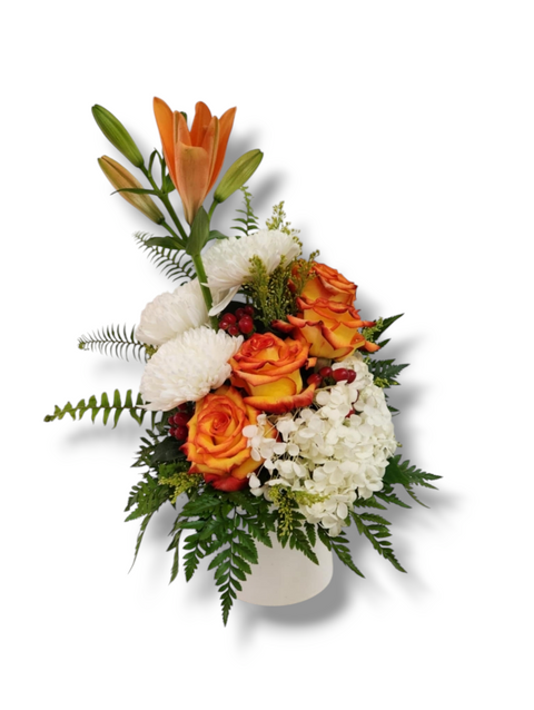 Bouquet vertical avec lys orange, roses bicolores, chrysanthèmes blancs, hydrangées et feuillage dans un vase blanc.