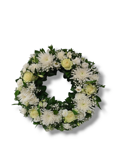 Couronne funéraire florale blanche avec roses crème, chrysanthèmes, gypsophile et feuillage vert – hommage sobre et raffiné.