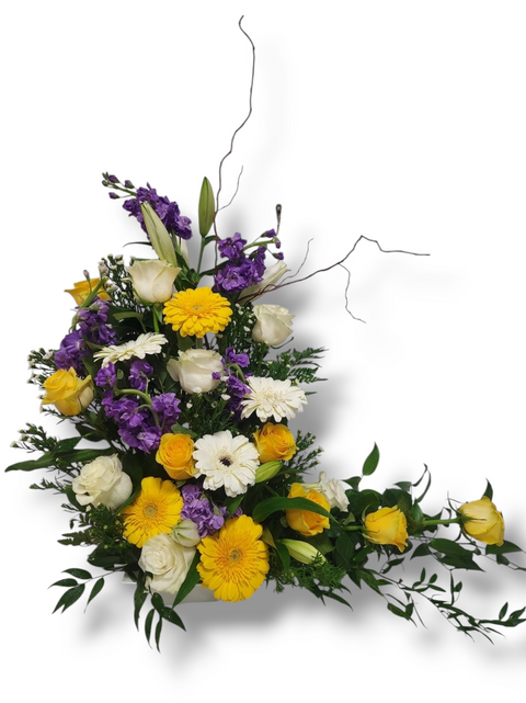 Arrangement floral funéraire vertical avec gerberas jaunes, roses blanches, fleurs violettes et feuillage, branches décoratives incluses.