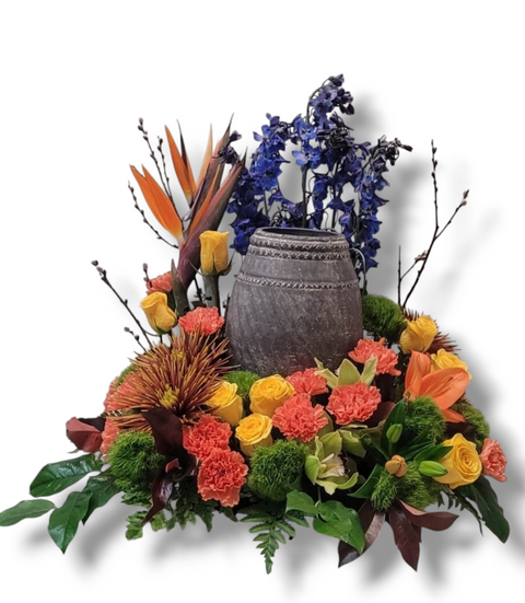 Arrangement floral pour urne funéraire avec roses jaunes, œillets orangés, oiseaux du paradis, orchidées, delphiniums bleus et verdure – modèle Rayonnement de Vie.