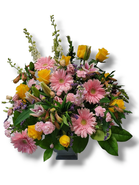 Bouquet rose et jaune dans vase carré avec gerberas, roses jaunes, lys et œillets – modèle Tendre Lumière.