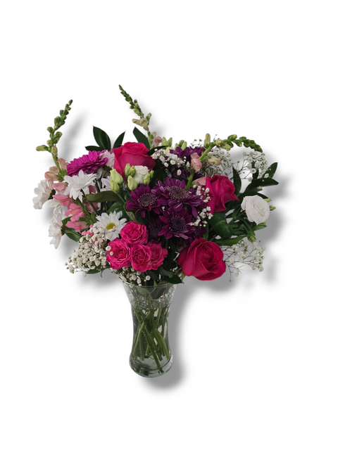 Bouquet romantique avec roses fuchsia, marguerites blanches, chrysanthèmes violets et fleurs mixtes dans un vase en verre.