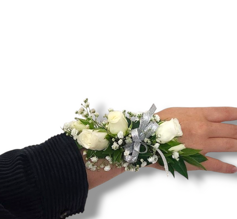 Bracelet de fleurs blanches avec mini roses, gypsophile et ruban argenté porté au poignet.