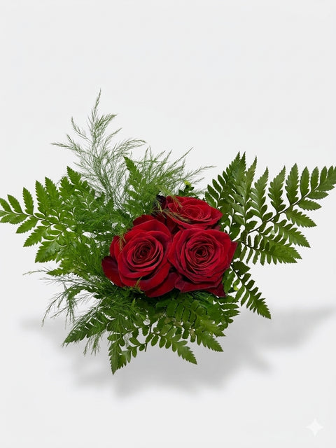 Bouquet de trois roses rouges fraîches entourées de feuilles de fougère verte