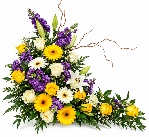 Arrangement funéraire en hauteur composé de roses, gerberas, lys et marguerites jaunes, blanches et violettes, avec des branches torsadées décoratives.