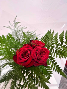 Trois roses rouges avec verdure