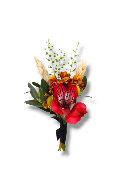 Boutonnière aux fleurs rouges et orangées avec verdure et accents de blé séché.

