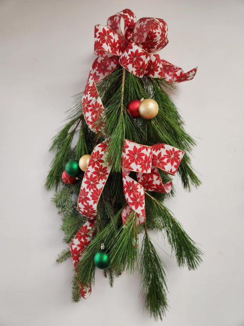 Décoration suspendue de Noël en sapinage naturel avec ruban poinsettia et boules rouges, vertes et dorées. Création artisanale Fleur de Guy.