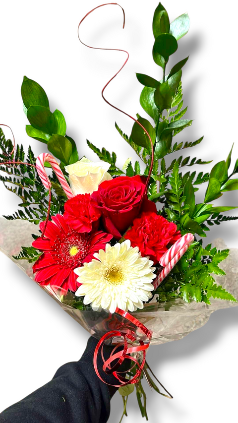 
Bouquet de Noël avec roses rouges et blanches, gerberas, feuillage et cannes de bonbon – modèle « Douceur de Noël » par Fleur de Guy.