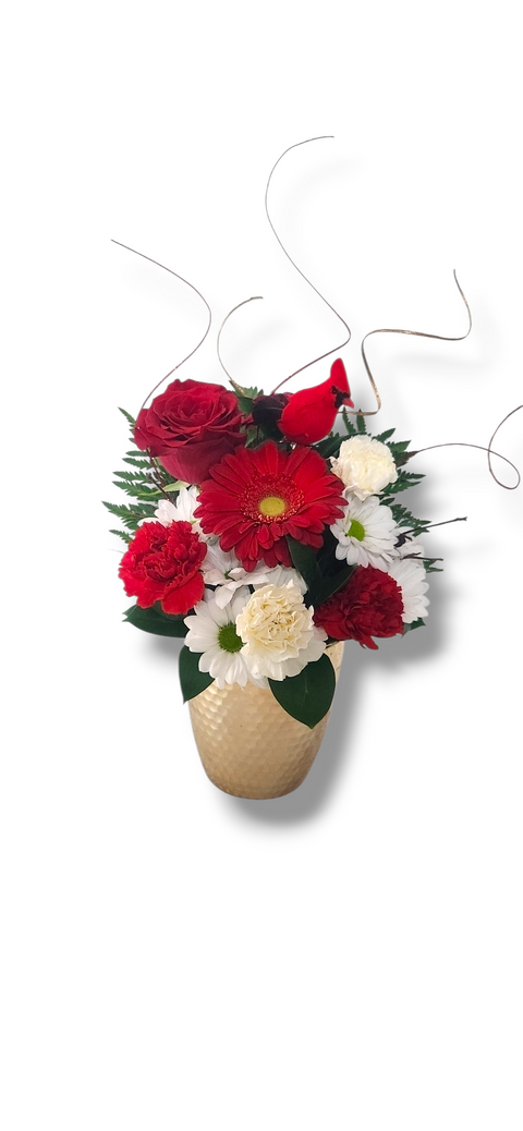 Arrangement floral de Noël avec fleurs rouges et blanches dans un vase doré brillant, orné d’un petit décor en bois – modèle « Or et Rouge » par Fleur de Guy.
