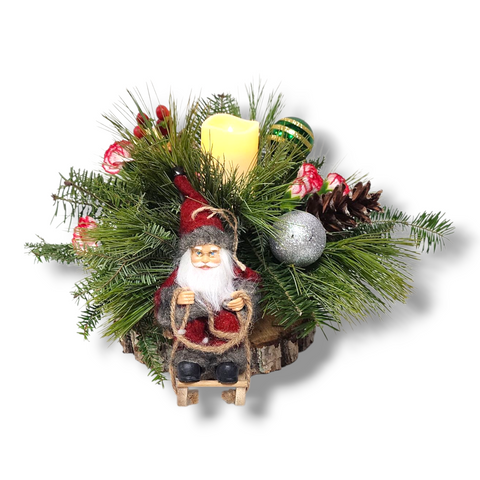 Centre de table de Noël avec chandelle LED, fleurs rouges, sapinage, cocottes et un Père Noël sur une luge – modèle « Père Noël en Traîneau » par Fleur de Guy.