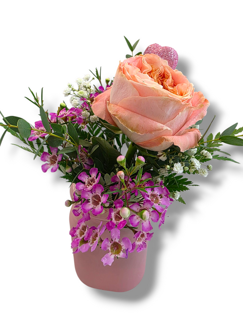 Arrangement floral avec rose pêche, fleurs sauvages roses et blanches dans un pot décoratif rose