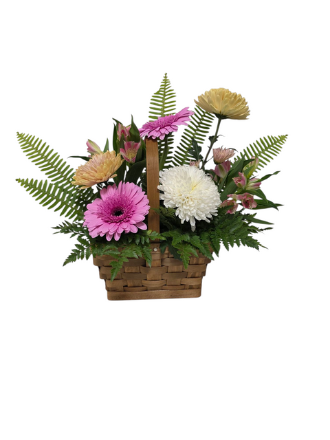 Panier floral en osier composé de fleurs pastel roses, blanches et crème avec feuillage vert, arrangement signé Fleur de Guy