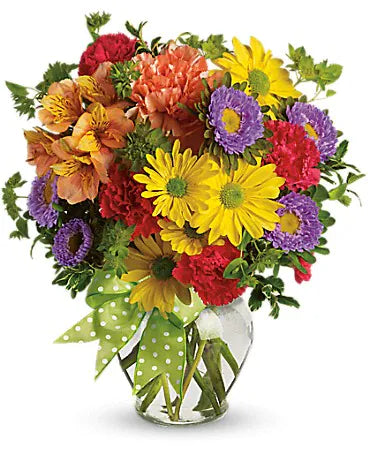 Bouquet de fleurs multicolores dans un vase avec ruban vert à pois, contenant des marguerites, œillets, asters et alstroemerias.